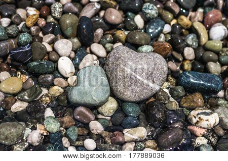 Sea pebbles of different sizes. Two stones in the form of hearts are washed by sea water.