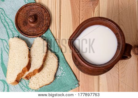 Milk and bread. Milk in a  clay jug. Wheat bread on a wooden background. Bio products.  Healthy food.