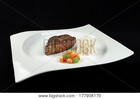 Slice Of Barbecued Cow Beef (picanha) With Rice, Tomato Salad And Basil Leaves On A White Dish With