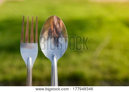 spoon and fork during picnic in the green grass background