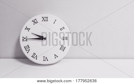 Closeup white clock for decorate show a quarter to ten o'clock or 9:45 a.m. on white wood desk and wallpaper textured background in black and white tone with copy space