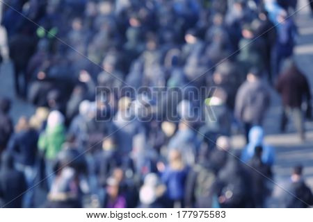 Crowd of people walking on busy city street, blurred view