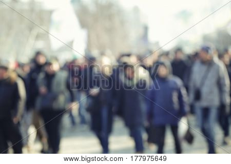 Crowd of people walking on busy city street, blurred view