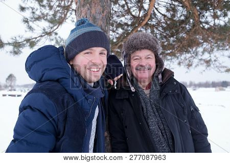 Two Mature Men Father And Son Dressed In Warm Clothes Sniling And Looking At Camera
