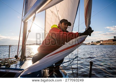 Handsome Man On Yacht Touches White Sail Called Assymetric Spinnaker, Works With Tackle In Sea At Su
