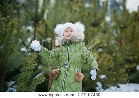Girl Playing Snowballs. Funny Little Girl Having Fun In Winter Park. Making Snowballs Happy Child Gi