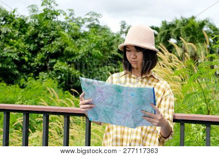 Portrait Of Young Asian Girl Traveler Holding Map While Standing In Outdoors Nature Background, Trav