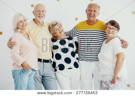 Smiling Group Of Elderly People Hugging Each Other During Photo Session