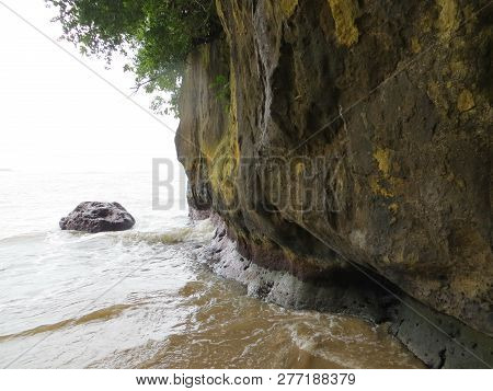 Anyer, Indonesia - June 25, 2018: The Waves Crashing Into The Large Rock On The Beach.