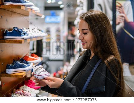Customer Woman Choosing Baby Clothes In The Shop