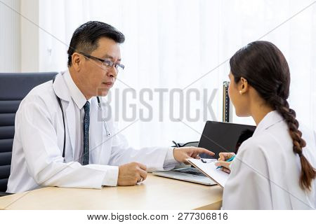 Two doctors in the hospital discuss the diagnos of the patient