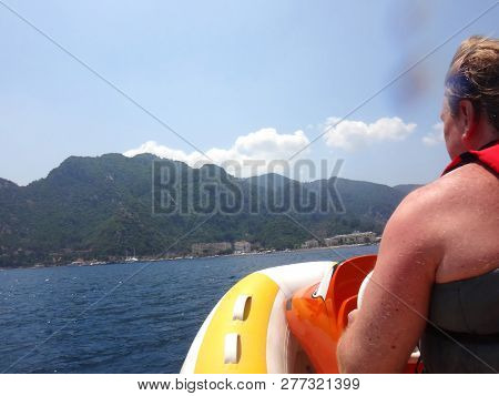 Big Man On A Rubber Motor Boat In The Sea And Splashing Water. Taking Pictures From The Boat