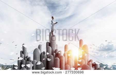 Young Female Doctor With Folder In Hands Satnding On Stone Column