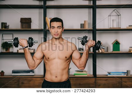 Muscular Bi-racial Man Exercising With Dumbbells In Living Room