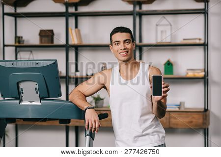 Handsome Bi-racial Man Smiling And Holding Smartphone With Blank Screen