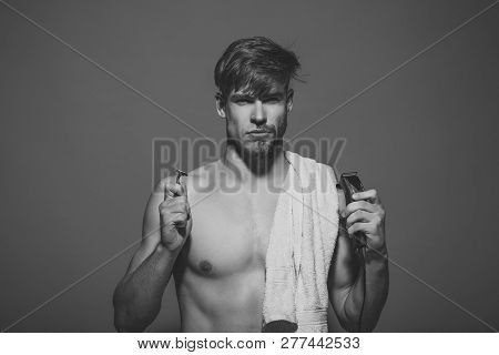 Macho With Half Bearded Face, Bath Towel On Muscular Torso. Man Choose Safety Or Electric Razor On B