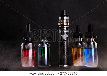 Electronic Cigarette And Bottles With Vape Liquid Within Vapor On Black Background