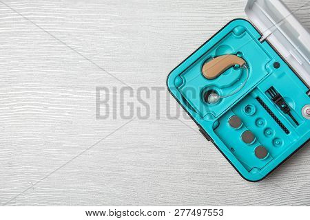 Case With Hearing Aid On White Wooden Background, Top View. Space For Text
