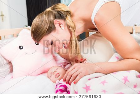 Close-up of happy mother looking at baby sleeping in the crib