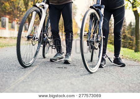 Legs And Feet Of Couple With Electrobikes Outdoors On A Road In Park.