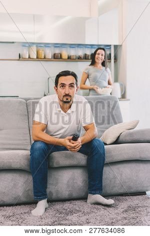 A Man Watches Tv, While His Wife Looks At Him