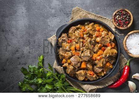 Beef Stew With Carrot Paprika And Tomatoes In Iron Pan On Black Background. Top View.