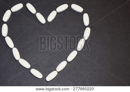 Heart Laid Out From Pills And Capsules On A Black Background