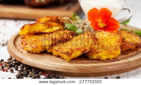 The Concept Of Ukrainian Cuisine. Draniki From Potatoes And Pumpkins, With Edible Flowers. Copy Spac