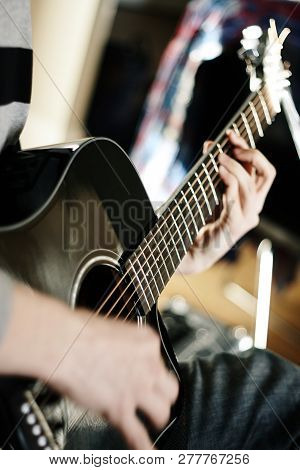 A Man Plays A Song On A Black Acoustic Six-string Guitar