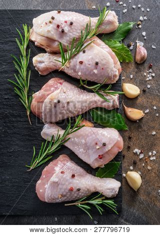 Chicken legs with spices and salt  ready for cooking on cutting board.