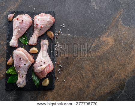 Chicken legs with spices and salt  ready for cooking on cutting board.