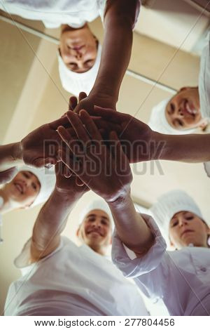Group of chefs formig hands stack om kitchen at hotel