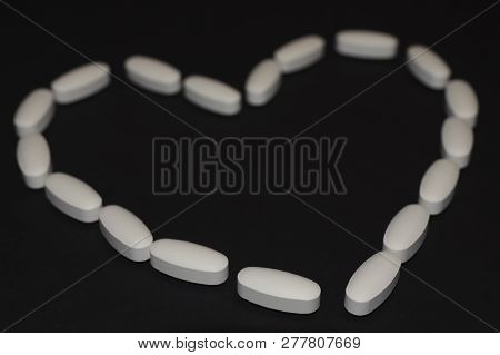 Heart Laid Out From Pills And Capsules On A Black Background