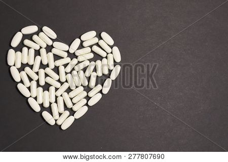 Heart Laid Out From Pills And Capsules On A Black Background