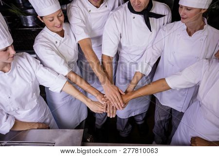 Group of chefs formig hands stack in kitchen at hotel