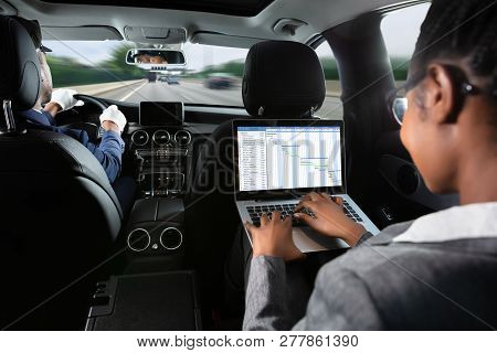 African Businesswoman Examining Gantt Chart On Laptop While Traveling By Car