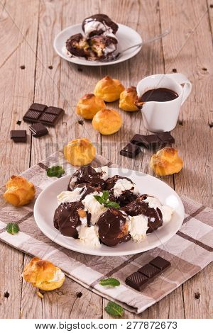 Chocolate Profiteroles With Whipped Cream On White Dish.