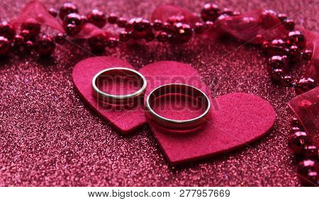 Close-up With Blur. Red Background With Two Rings And A Heart, Near Small Glass Hearts