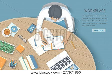 Мan Writing Notes In A Notebook At A Round Wooden Desk. Workplace Desktop Workspace Office Supplies,