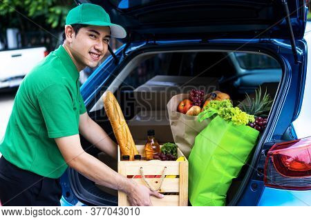 Asian Delivery Man In Green T-shirt Delivering Food, Fruit, Joice And Vegetable To Home - Online Gro