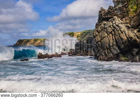 Close up shot how Atlantic ocean wave breaks on the big rocky stone on the beautiful Moinhos beach of Sao Miguel island of Azores, Portugal