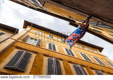 Narrow Street And Banner Of The Contrads In Siena. Tuscany, Italy