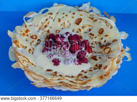 Breakfast Pancakes With Condensed Milk And Raspberries On A Blue Background