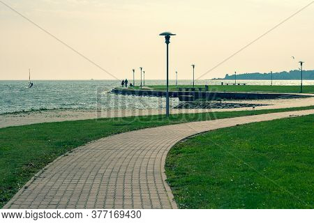 A Winding Footpath Along The Shores Of The Curonian Strait In Neringa. A Couple Walks Along A Path B