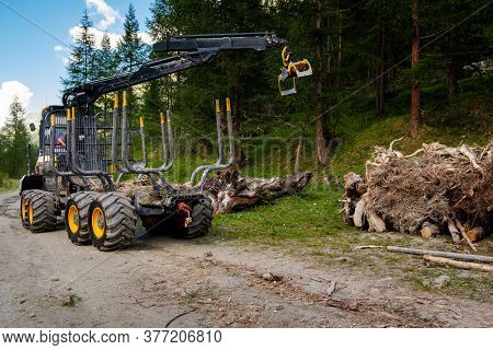 Zinal, Valais, Switzerland : Logging Machinery With Hydraulic Arm Loading Cut Trees For Timber Or Fi