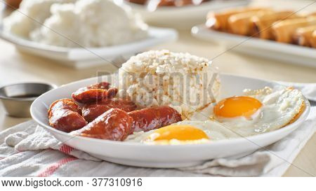 filipino silog breakfast with garlic fried rice, longsilog, and two sunny side up eggs