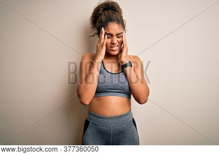 Young african american sportswoman doing sport wearing sportswear over white background with hand on headache because stress. Suffering migraine.