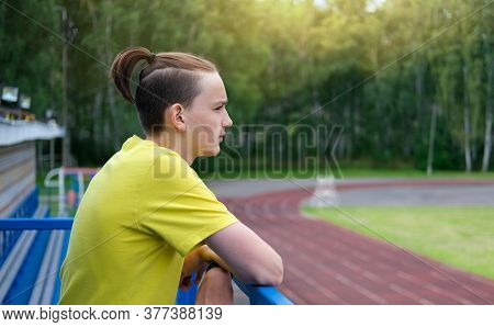 Teenager Boy With Topknot Haicut. Top Knot Or Samurai Men Hairstyle. Teen Guy Looking At The Stadium