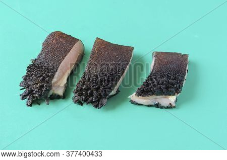 Pieces Of Raw Cow Stomach On Turquoise. Random Pieces Black Unpeeled Tripe With Grass Residues. Beef
