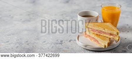 Ham And Cheese Sandwich, Coffee With Milk And Orange Juice On Table In Coffee Shop. Typical Breakfas
